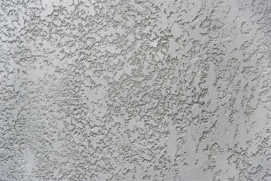 Close-up of a light gray stucco wall with a rough, textured surface and irregular patterns, showcasing the expert plaster application provided by Stucco Services Central Florida.